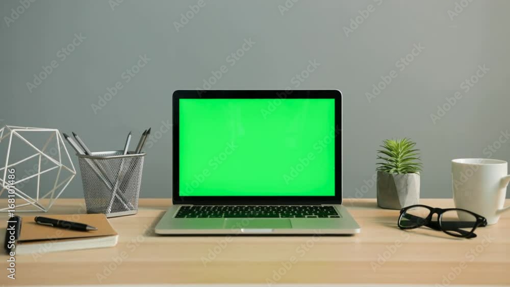 View of laptop with green screen on the office table. Chroma key. Close up shot.