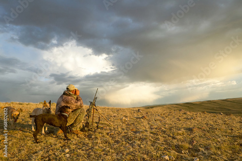 Sunrise hunter and dogs in dramatic arid landscape