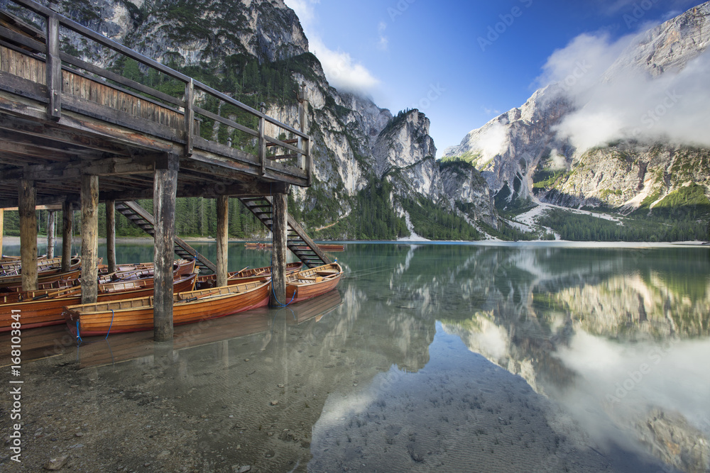boats under embankment on the lake with sun and clouds in Italy