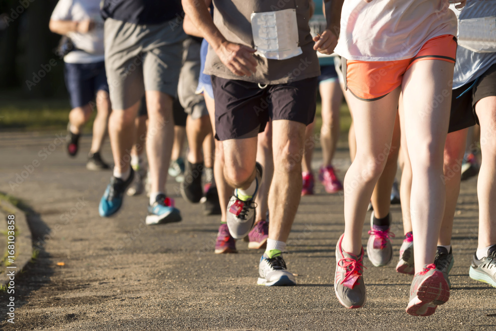 Group of runners racing a 5K on a dirt path Group of runners racing a 5K on a dirt path
