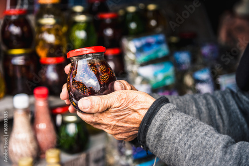 Fototapeta Naklejka Na Ścianę i Meble -  Wrinkled old female hands hold jar with jam