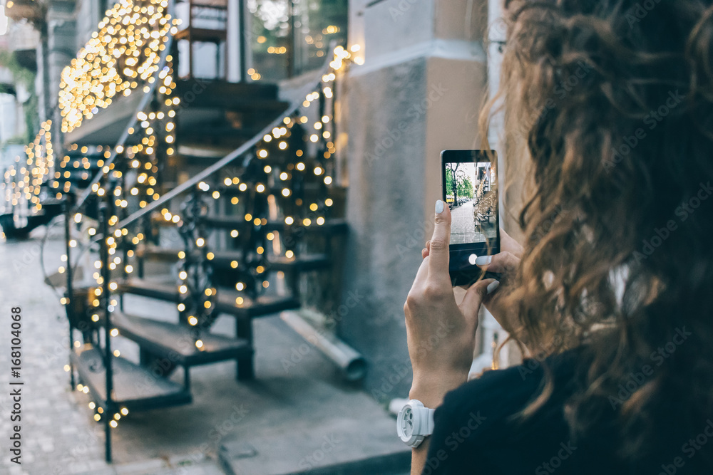 Obraz premium Woman is taking pictures of the city's summer scenery on the phone