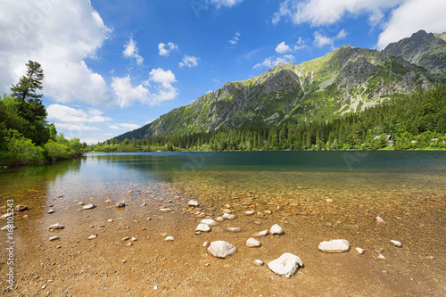 The sunset landscape of the picturesque lake surrounded by mountain peaks and canyons