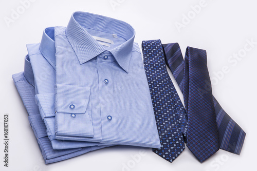 Three blue men's shirts folded in a pack and ties on a white background.
