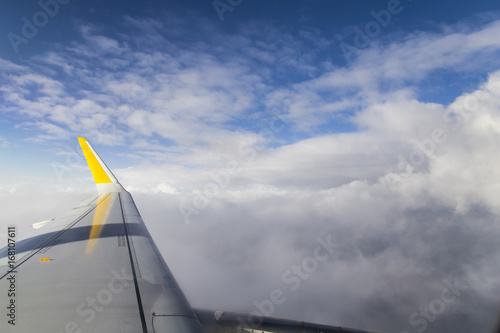 Flying on an airplane wing on a blue cloudy sky