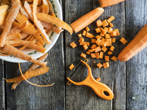 Carrots, peeled carrots in a bowl and a peeler
