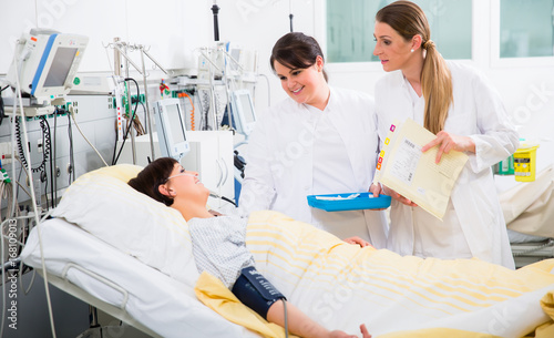 Doctors visiting woman patient during medical round at ICU of hospital photo