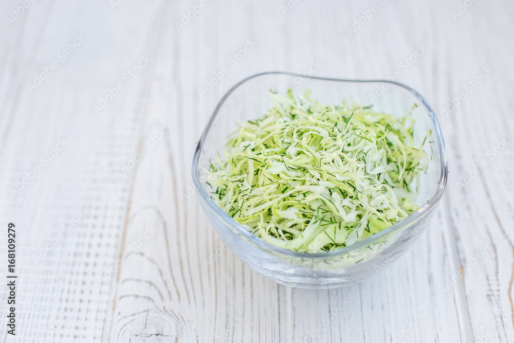 Green cabbage in a glass bowl. Salad. Wooden background. Copy space. The concept is healthy food, diet, vegan. Green cabbage in a glass bowl. Salad. Wooden background. Copy space. The concept is healthy food, diet, vegan.