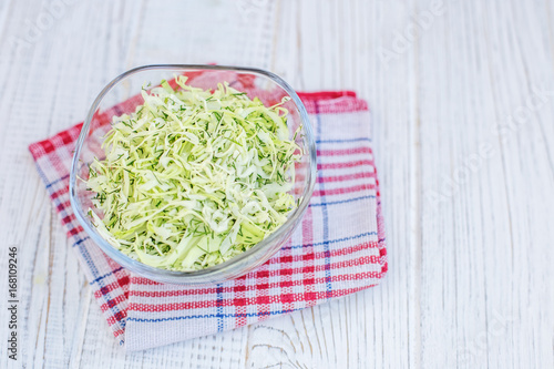 Green cabbage in a glass bowl. Salad. White background. Copy space. The concept is healthy food, diet, vegan.