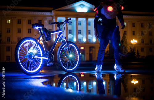 Glowing bicycle is reflected in the water. Nearby is a man in luminous shoes-2