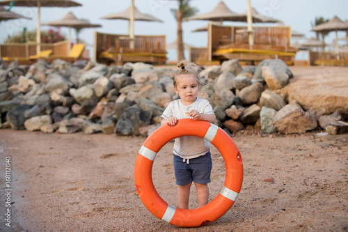 Little boy child standing and holding life ring at beach