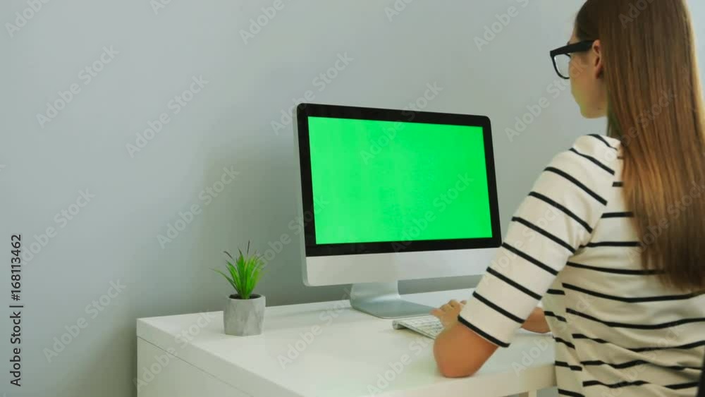 Portrait of young business woman in the stylish shirt working on the computer with green screen in the office background. Chroma key. Portrait of young business woman in the stylish shirt working on the computer with green screen in the office background. Chroma key.