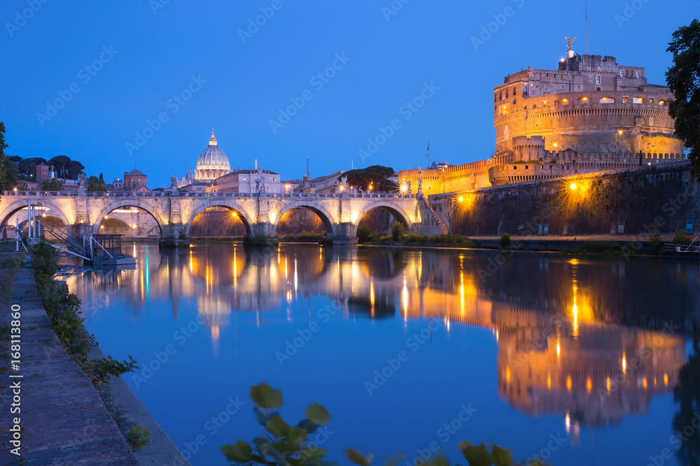 Saint Angel castle and bridge with mirror reflection in Tiber River during morning blue hour in Rome, Italy.
