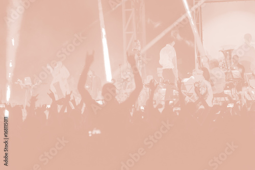 Blurred creative art background. Rear view of crowd with arms outstretched at concert. cheering crowd at rock concert. silhouettes of concert crowd in front of bright stage lights.