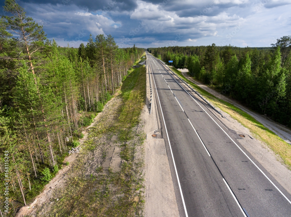 Empty asphalt country road in northern Karelia. Thunderclouds over forest. Russia