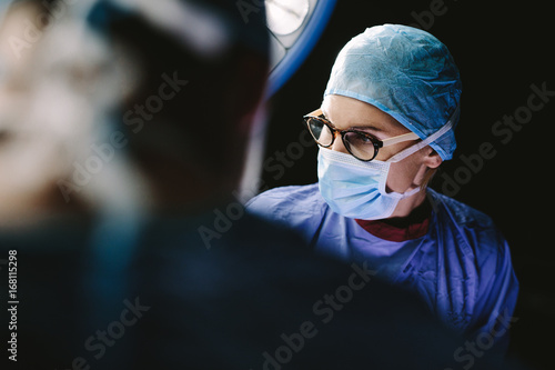 Female surgeon with team performing surgery photo