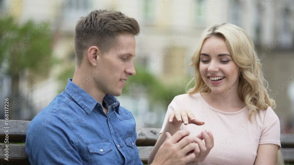 Guy taking ring, putting on girlfriends finger and kissing her, engagement Guy taking ring, putting on girlfriends finger and kissing her, engagement