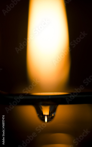 Reflection of a lit candle in a drop of water