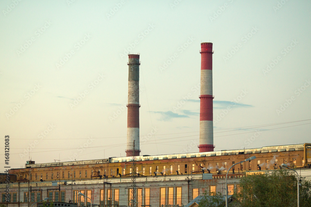 Production plant against the sky with pipes for the exhaust of waste in the form of smoke