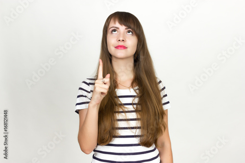 Young happy girl pointing up to product, isolated on gray background