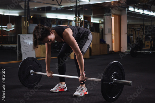 Pretty young woman doing squats at the gym