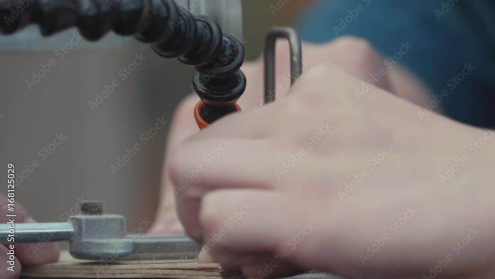 Woodworker hands cutting pattern out pile wood on fast jumping jig saw machine, close up shot Woodworker hands cutting pattern out pile wood on fast jumping jig saw machine, close up shot