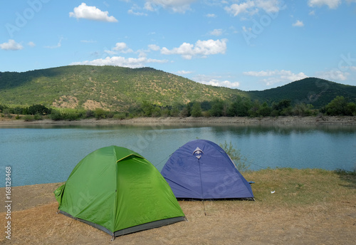 Blue and green tent on the shore of a mountain lake