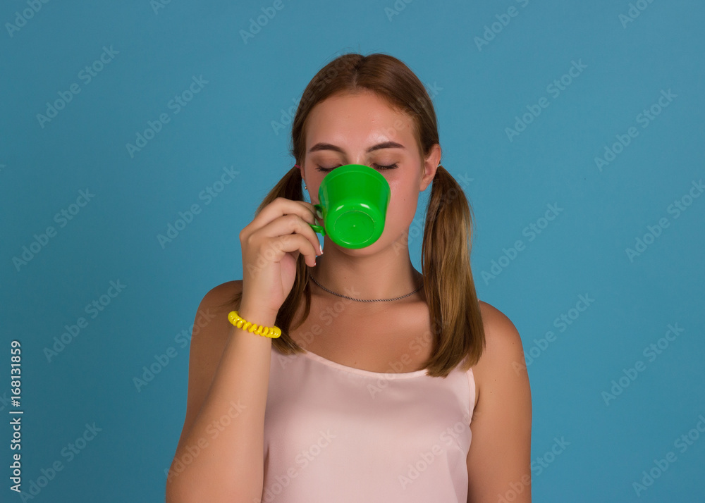 Young pretty girl drinks a cup of hot beverage, studio Young pretty girl drinks a cup of hot beverage, studio