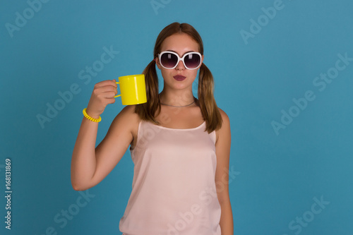 Young pretty girl drinks a cup of hot beverage, studio 