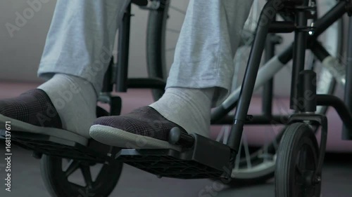 Feet of paralyzed male sitting in wheelchair socially vulnerable disabled person