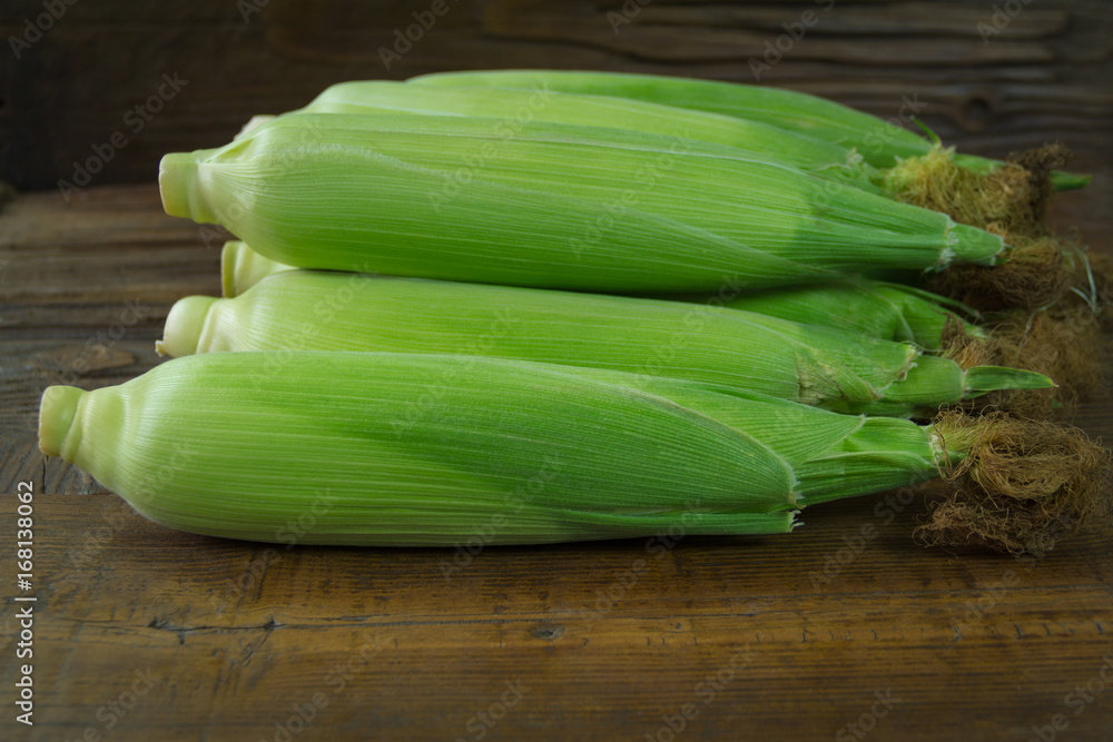 Freshly picked unpolished corn on a wooden background Freshly picked unpolished corn on a wooden background
