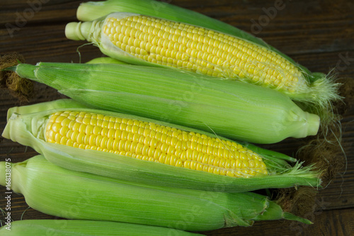 Freshly picked unpolished corn on a wooden background
