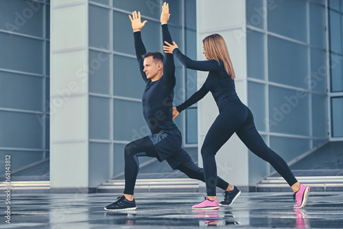 Fitness couple is stretching over modern building background.