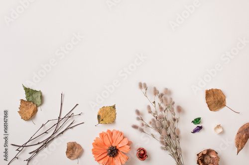 Autumn composition: fallen leaves, dry petals, dried flowers and plants on white with craft rustic paper with red flower. Top view. Flat lay.