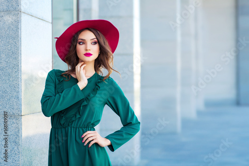 Young woman in red hat, posing in green dress