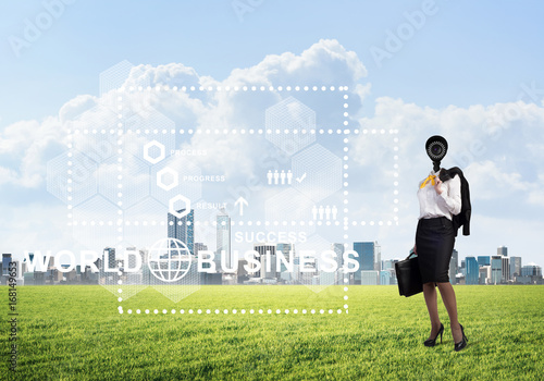 Camera headed woman standing on green grass against modern cityscape