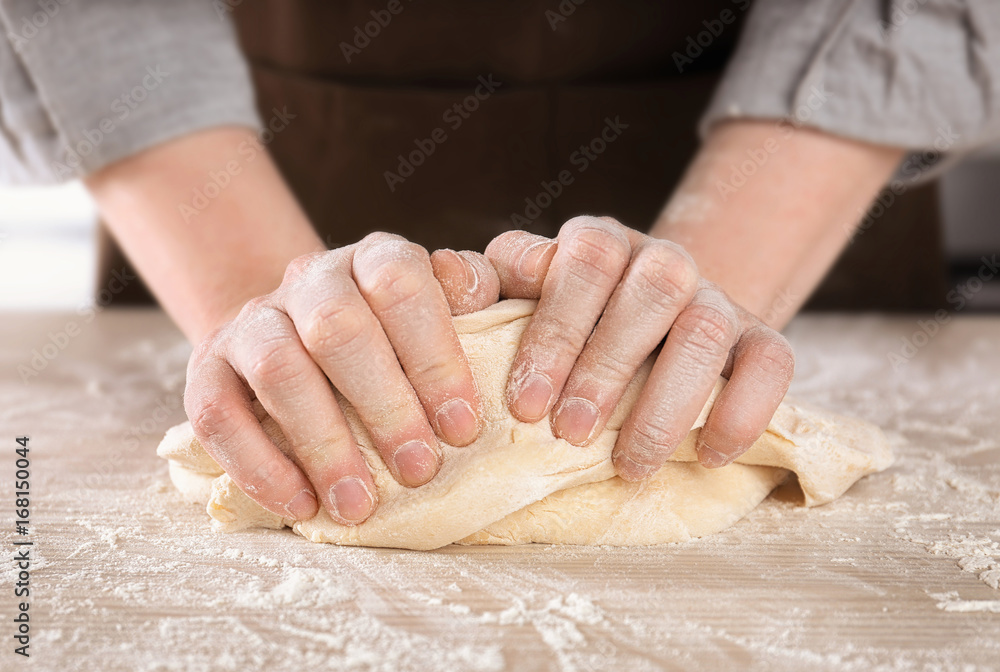 Woman kneading dough on table in kitchen