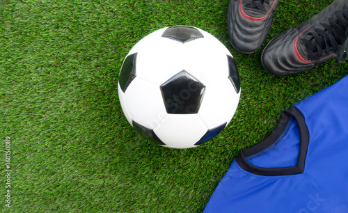 Soccer concept : Football (soccer ball), old soccer boots, blue soccer kit (t-shirt)  on green grass background. Flat lay with copy space.