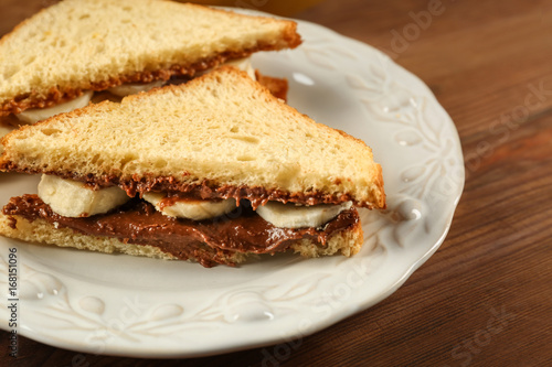 Tasty sandwiches with peanut butter and sliced banana on plate
