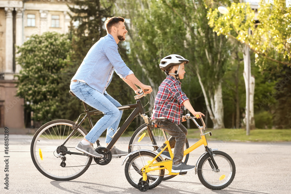 Fototapeta premium Dad and son riding bicycles outdoors