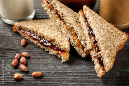 Tasty sandwiches with peanut butter and jam on table