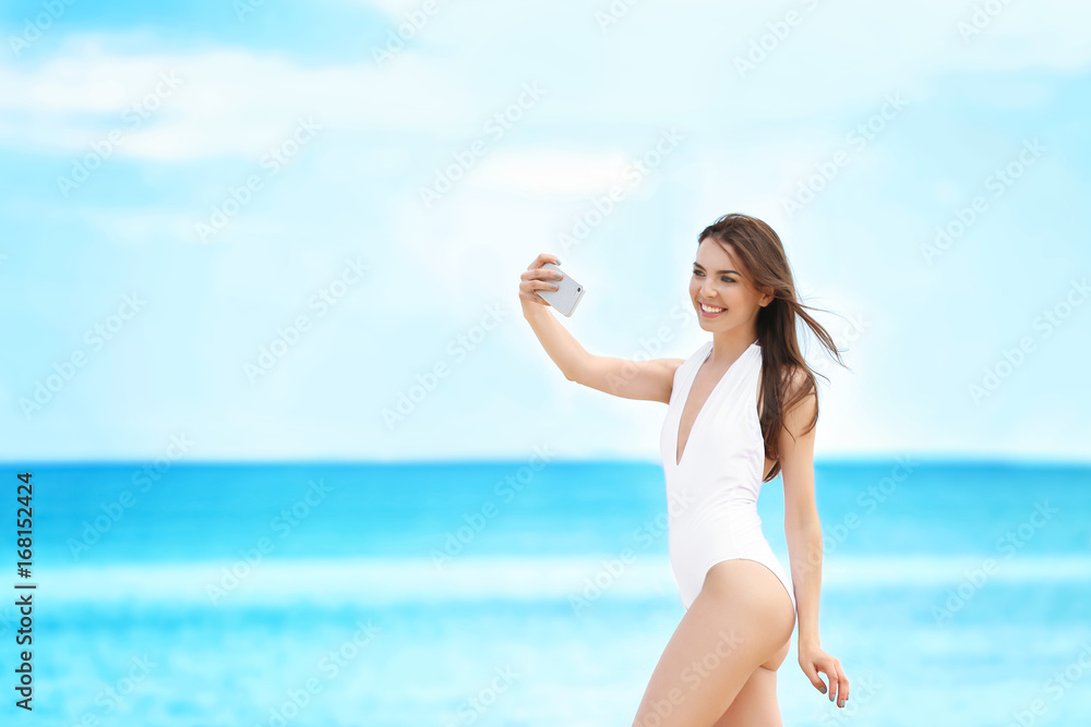 Beautiful young woman taking selfie near sea on summer day Beautiful young woman taking selfie near sea on summer day