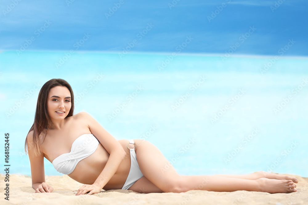 Beautiful young woman in bikini on sea beach