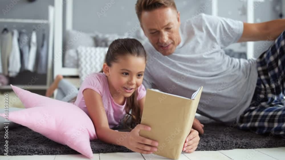 Cheerful little girl reading a book at home Cheerful little girl reading a book at home