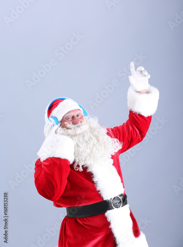 Santa Claus listening to music on color background