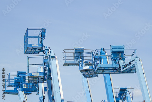 Basket of multiple forklifts are old of blue on blue sky background