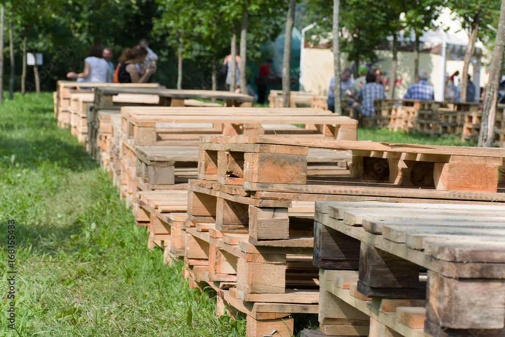 Wooden pallets outdoors in a summer park against a background of green grass for a rest of people