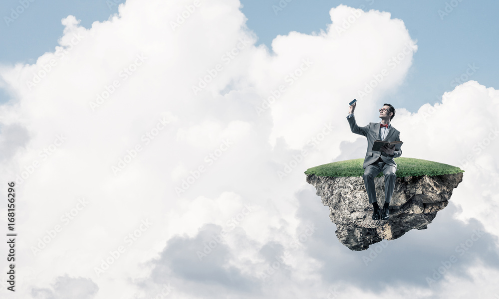 Young businessman or student floating in sky and studying the sc Young businessman or student floating in sky and studying the sc