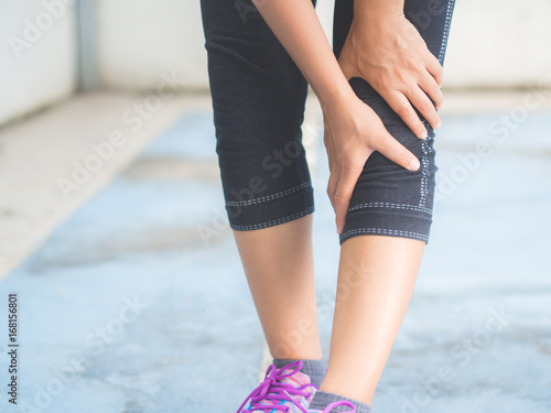 Closeup runner sport knee injury. Woman in pain while running. Sport injuries concept.
