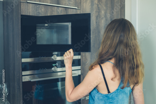 Young woman opening the microwave